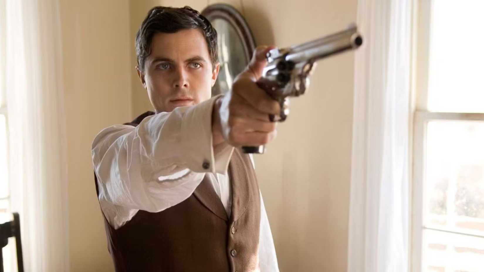 Casey Affleck como Robert Ford aponta um revólver para a nuca de Jesse James enquanto está dentro de uma sala vazia antes de executá-lo em O Assassinato de Jesse James, do Covarde Robert Ford