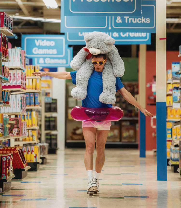 Channing Tatum's Jeff walking down an aisle with a teddy bear and swimming donut in Roofman-1