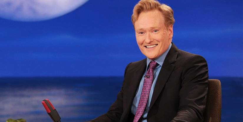 Conan O'Brien sitting behind his late-night desk
