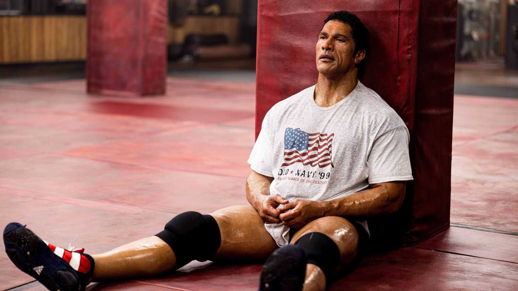 Dwayne Johnson como Mark Kerr sentado no chão de uma academia em The Smashing Machine