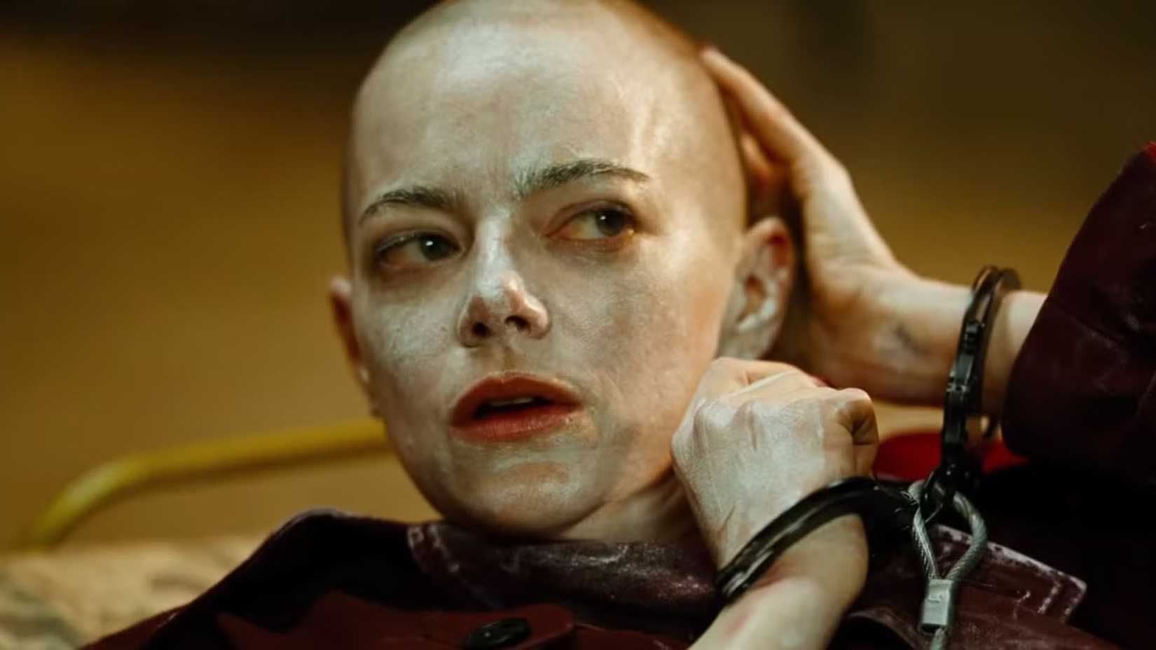 Emma Stone algemada e tocando a cabeça raspada em Bugonia