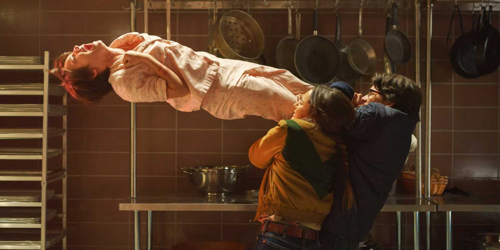 Ernesto and Mustand hold back Gwen's suspended body from the oven in Black Phone 2
