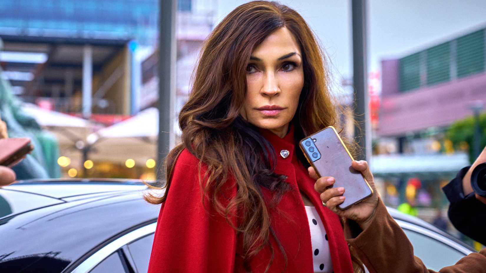 Famke Janssen como Betty, confiante e cercada por jornalistas em Amsterdam Empire.