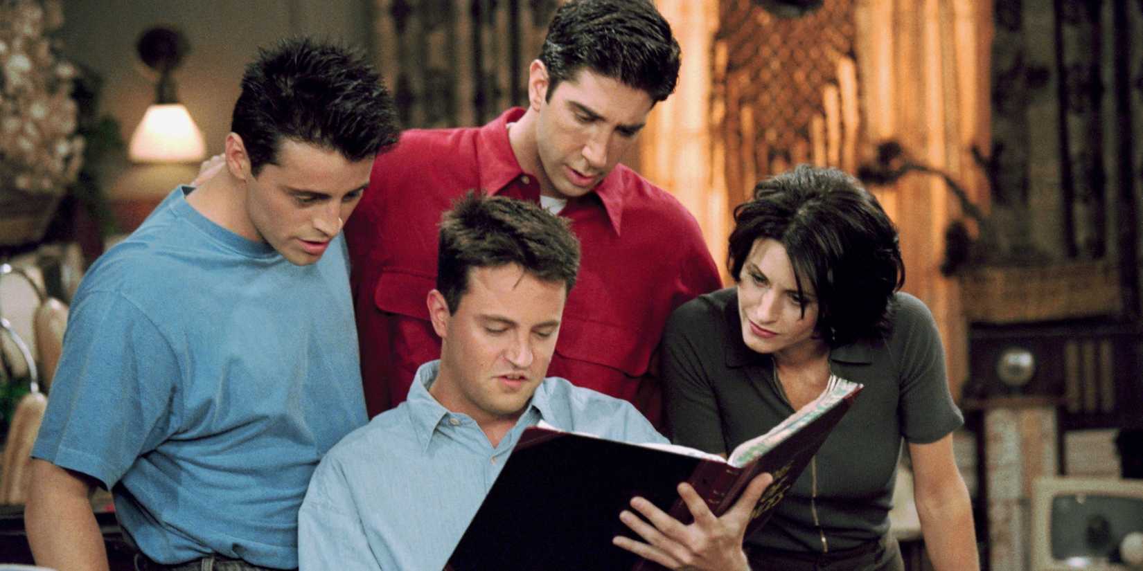 Joey, Ross, Chandler, and Monica looking at a book on Friends