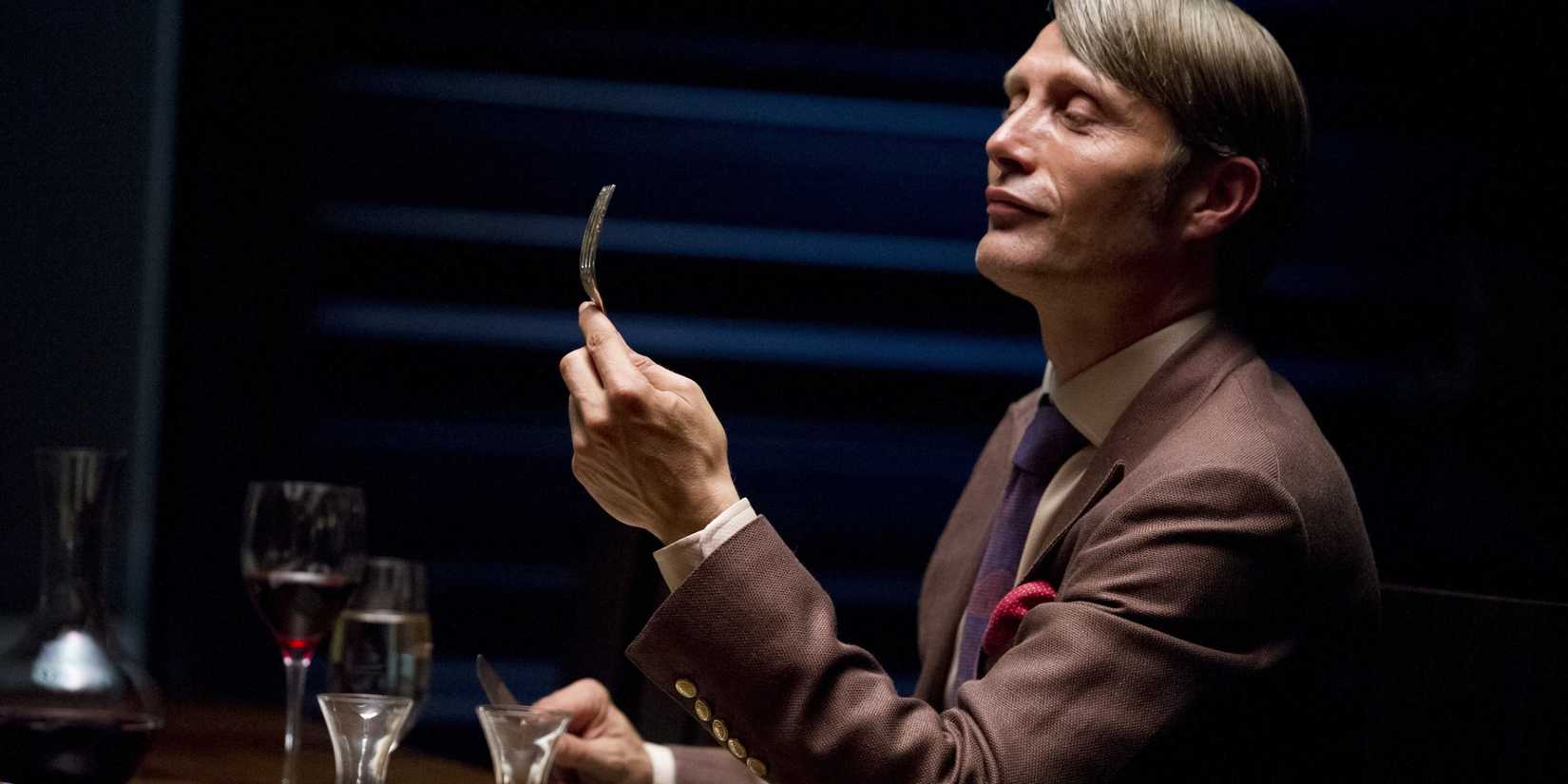 Hannibal Lecter (Mads Mikkelsen) examinando um garfo em uma mesa de jantar na primeira temporada de Hannibal