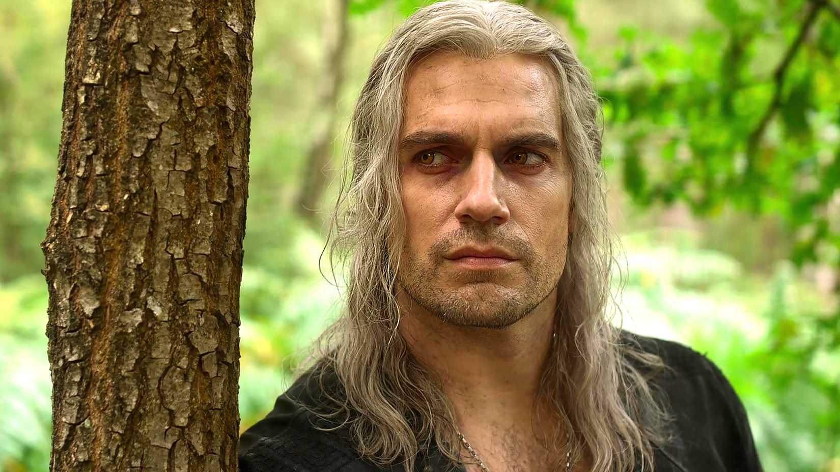 Henry Cavill's Geralt leaning against a tree in The Witcher season 3