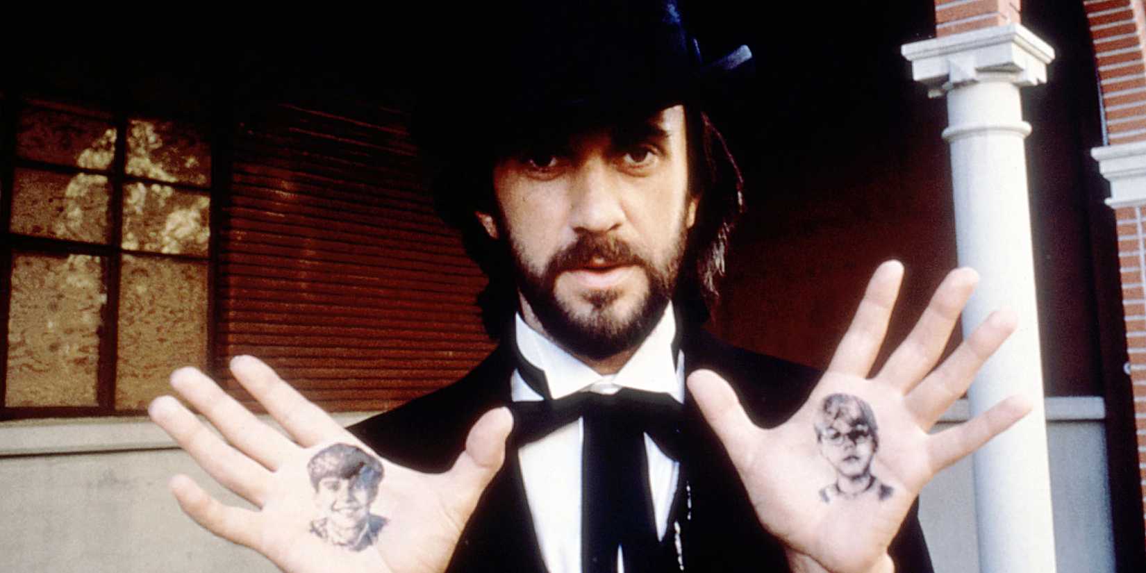 Jonathan Pryce shows his palms adorned with ink drawings of children's faces in a scene from Something Wicked This Way Comes