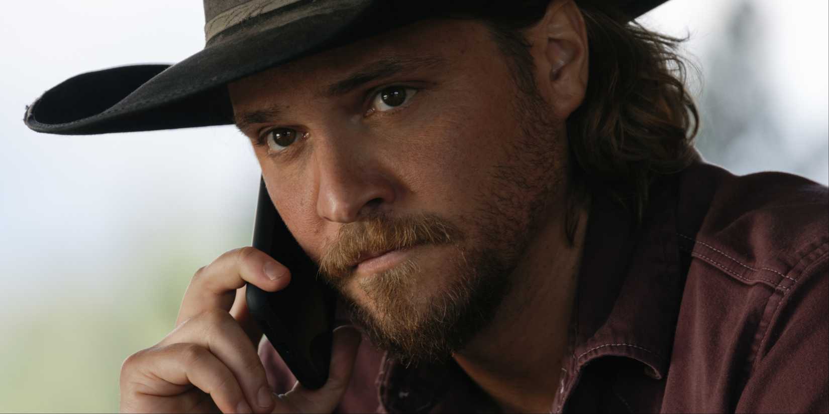 Kayce Dutton (Luke Grimes) on the phone looking concerned in Yellowstone