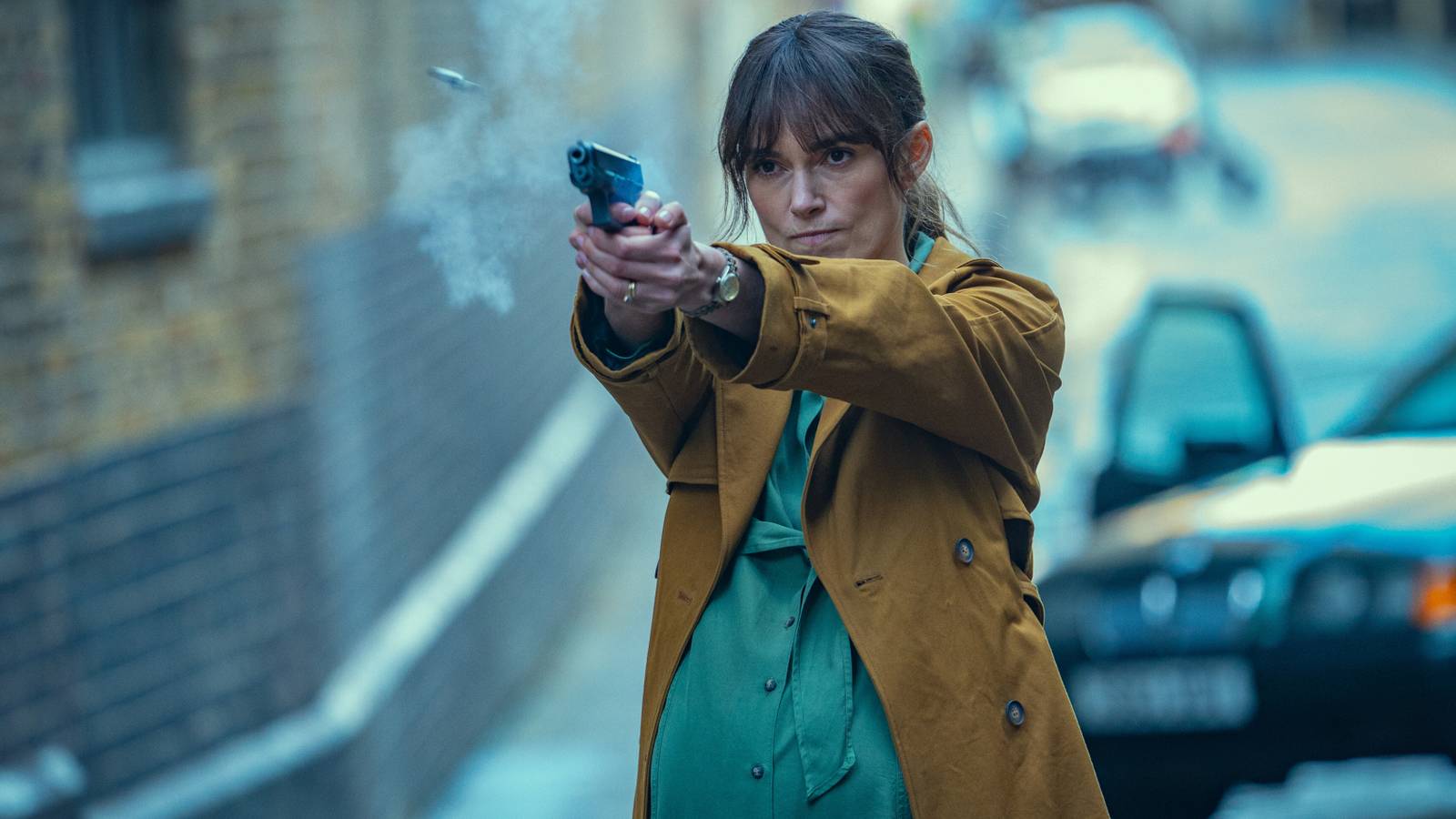 Keira Knightley as Helen firing a pistol in front of a car in Black Doves season 1