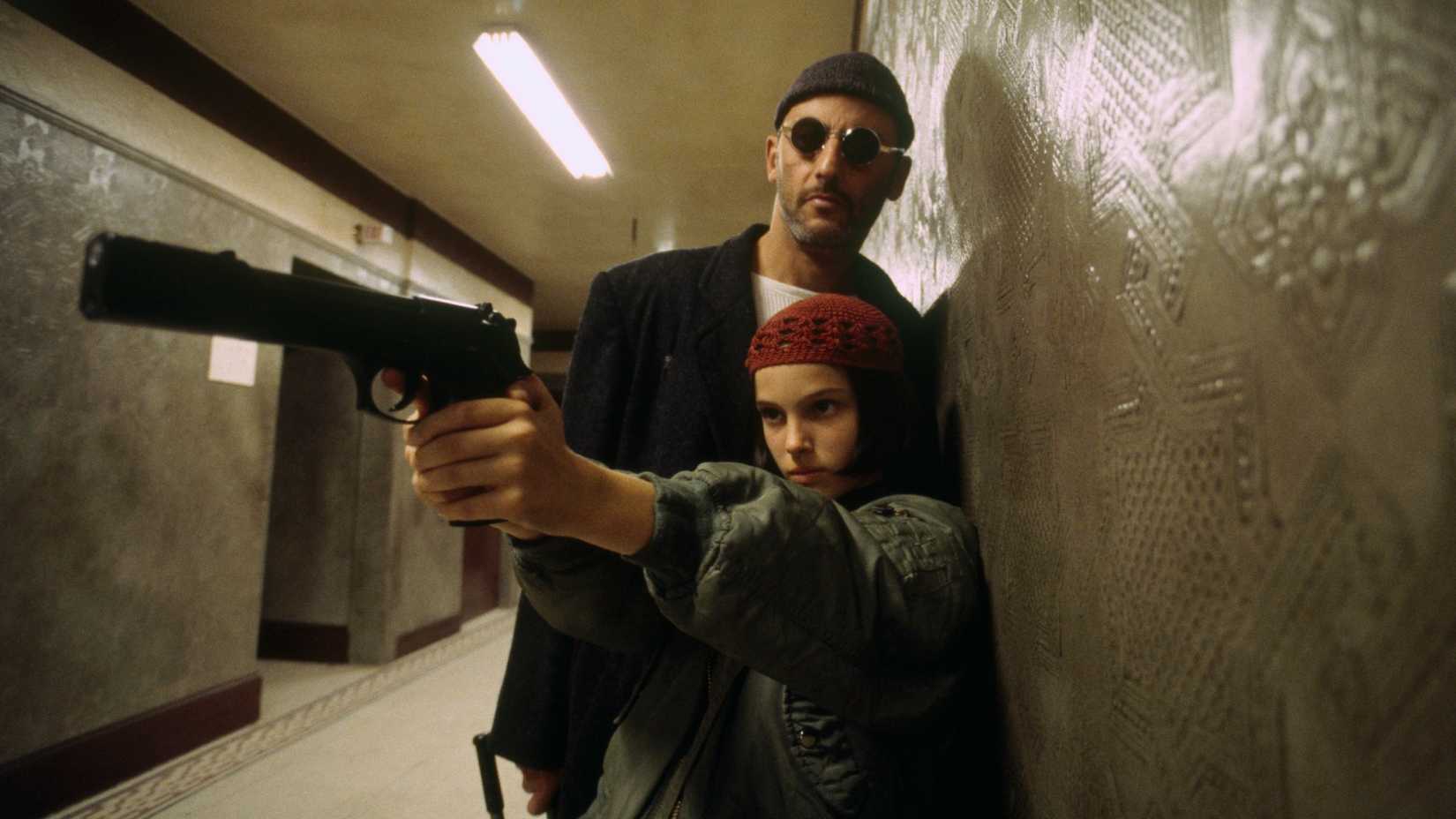 Mathilda points a gun while Leon watches in a hallway in Leon The Professional 