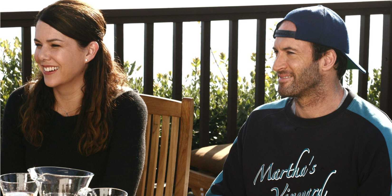Lorelai (Lauren Graham) and Luke (Scott Patterson) sitting at a table and smiling at Martha's Vineyard in Gilmore Girls