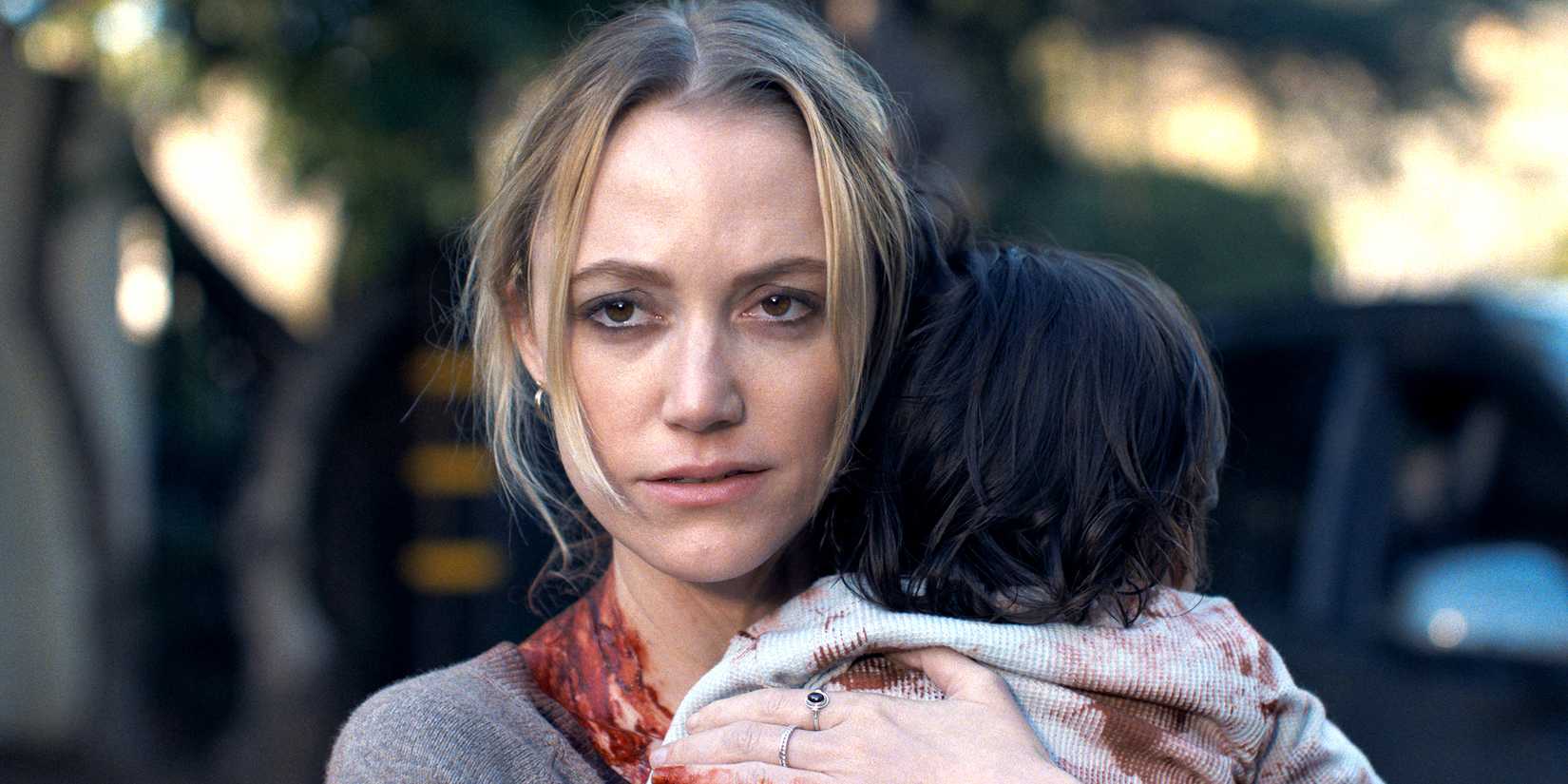 Maika Monroe as Polly looking suspiciously while holding Josie in The Hand That Rocks the Cradle
