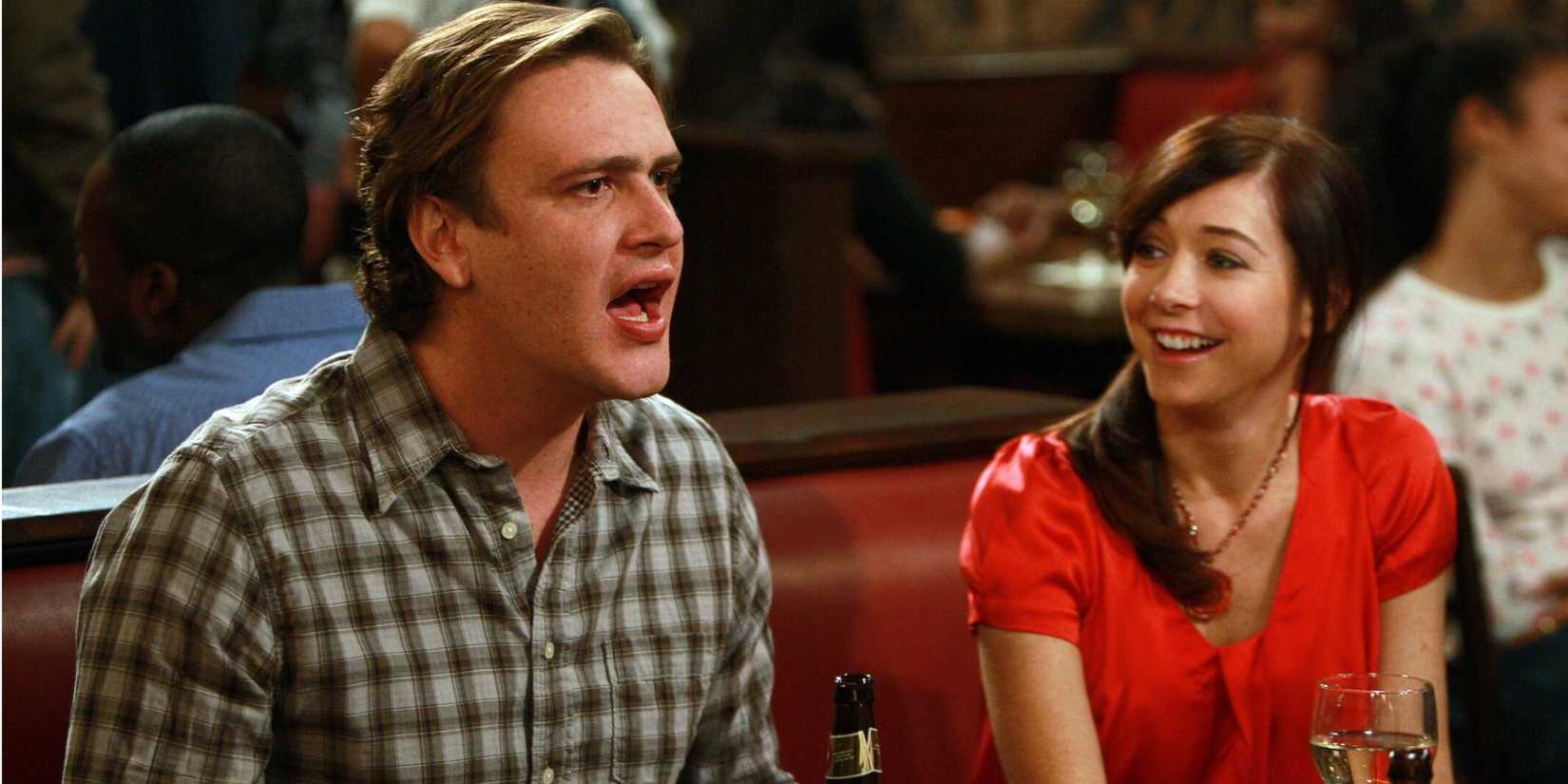 Marshall (Jason Segel) com raiva enquanto Lily sorri na cabine do Maclaren's em How I Met Your Mother.