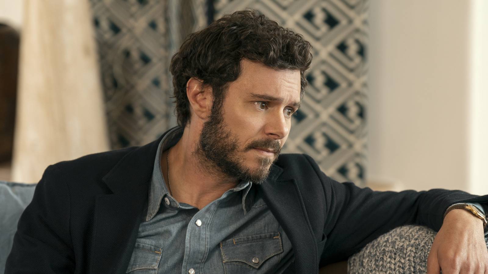 Noah sits on a couch looking upset in Nobody Wants This season 2 episode 3.