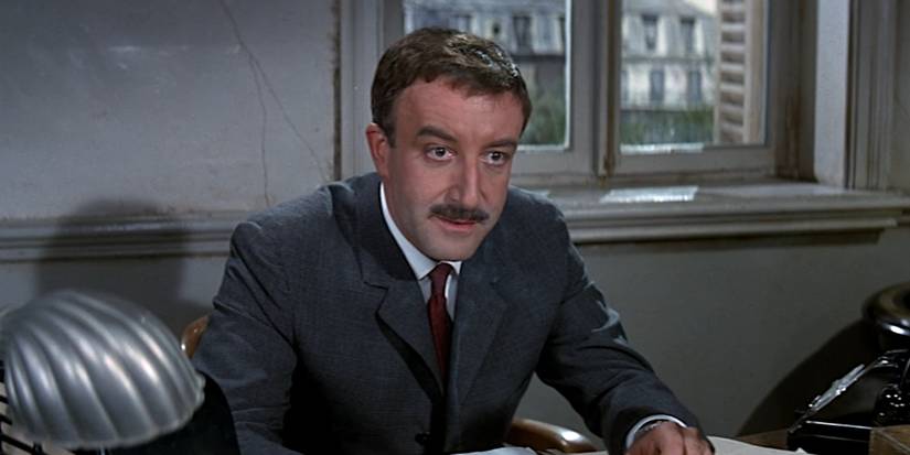 Peter Sellers talks from behind a desk in a scene from A Shot in the Dark