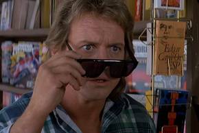 Roddy Piper as Nada peeks past his glasses in They Live