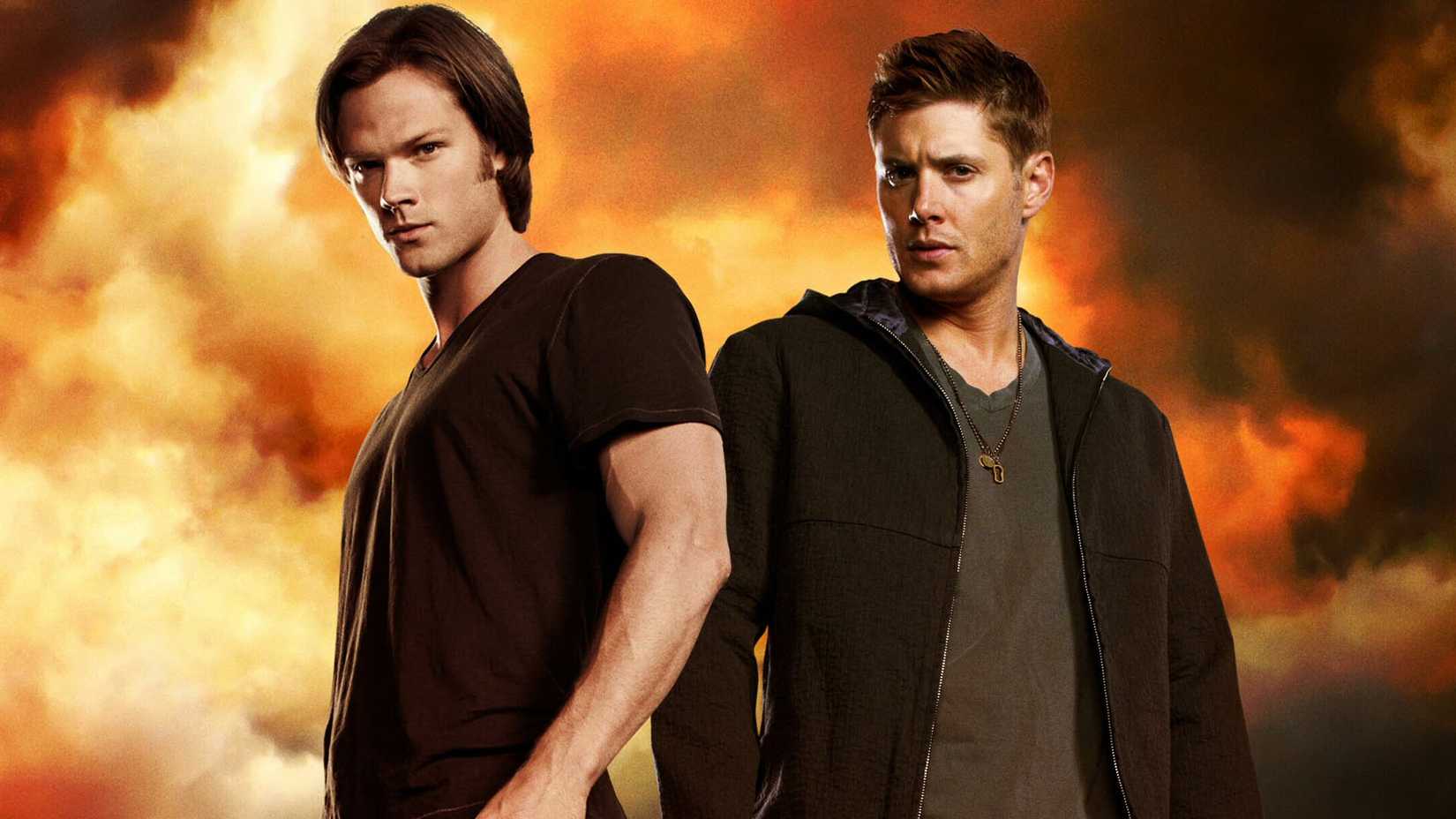 Sam and Dean Winchester stand together looking at the camera in front of cloudy orange clouds in Supernatural poster