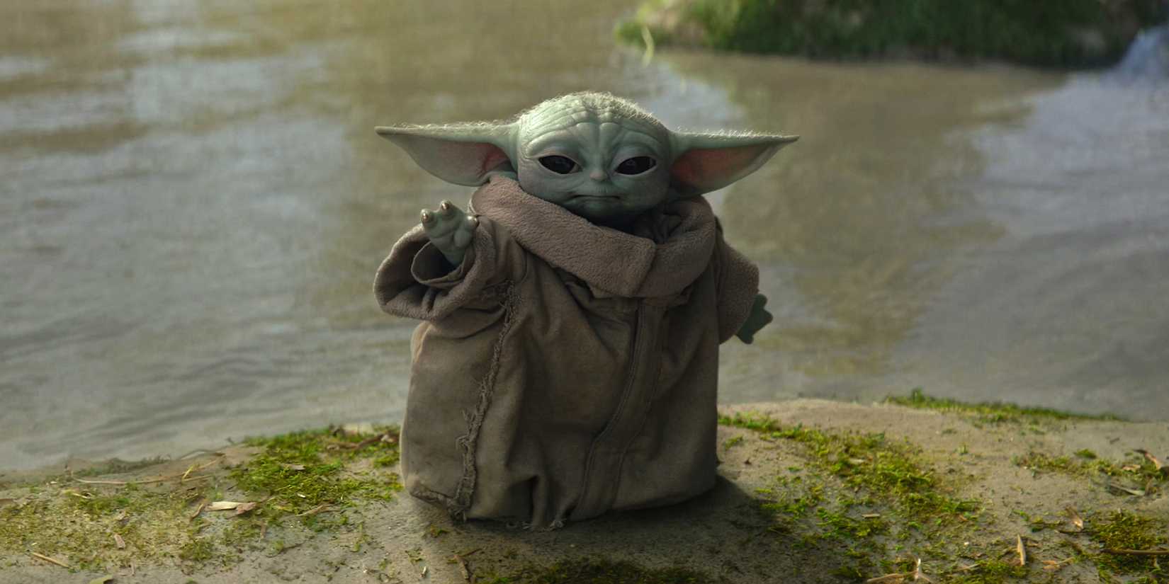 Grogu's eyes narrow in concentration as he stretches out a hand to use the Force on Ossus.