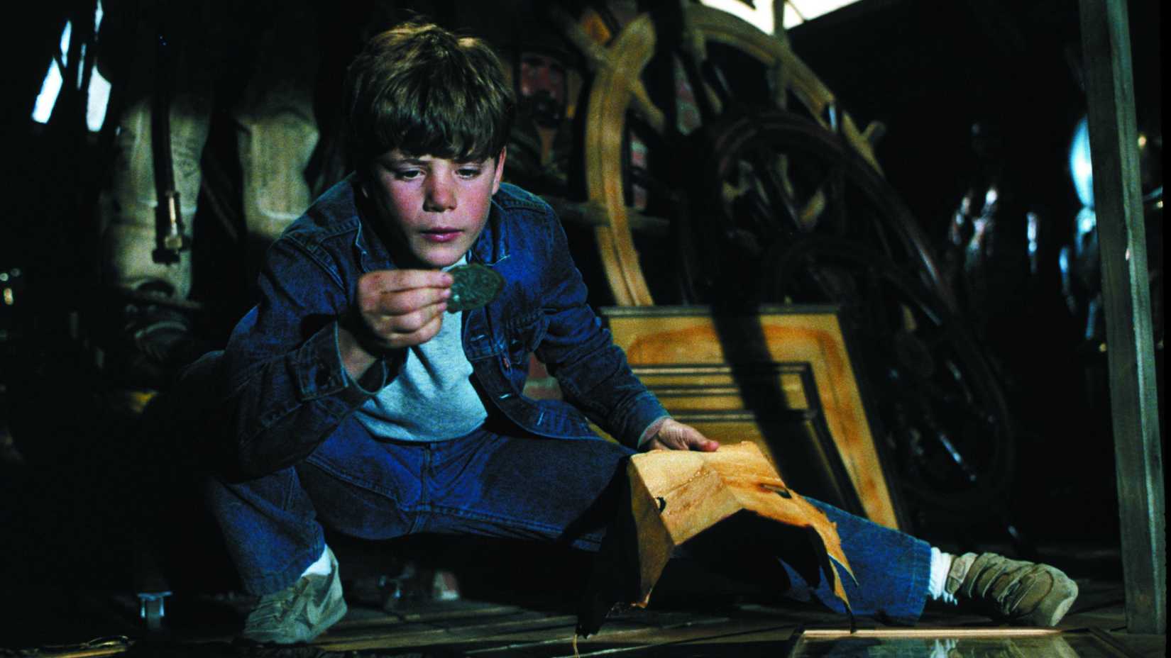 Sean Astin holding a coin and looking down at it in The Goonies
