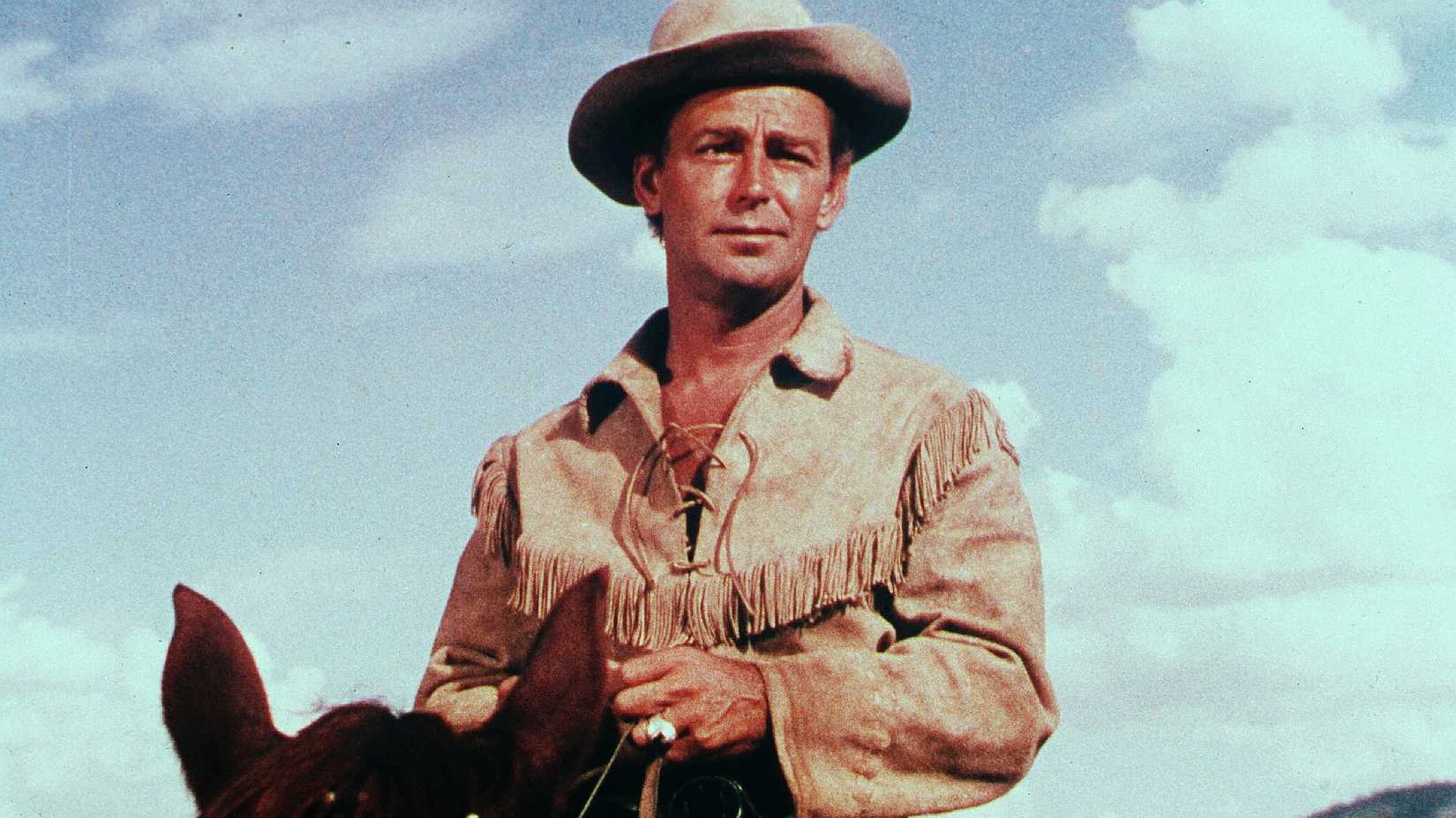Alan Ladd looks on sternly while riding a horse in Shane