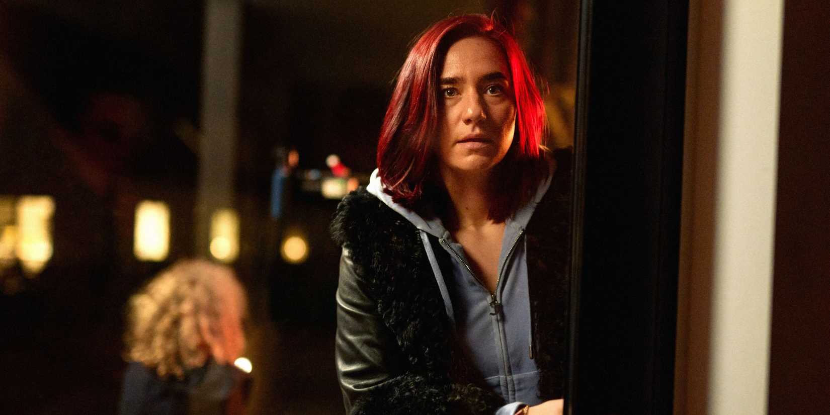 Ashley (Maria Cordsen) olhando ao redor de um muro na série The Asset.