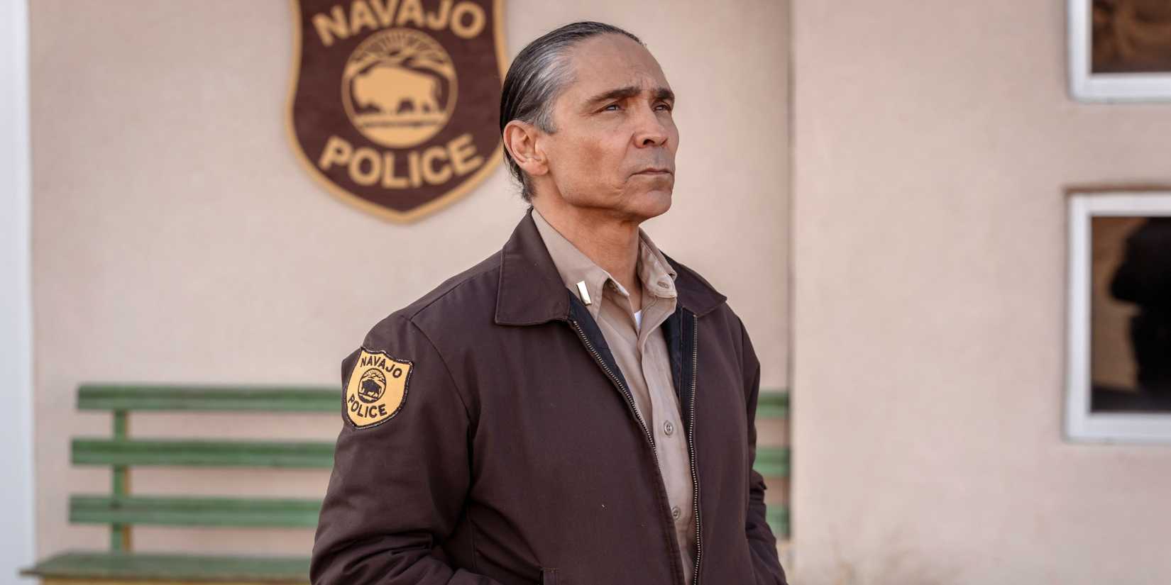 Джо (Зан Макларнон) в форме идет перед знаком полиции Навахо в Dark Winds