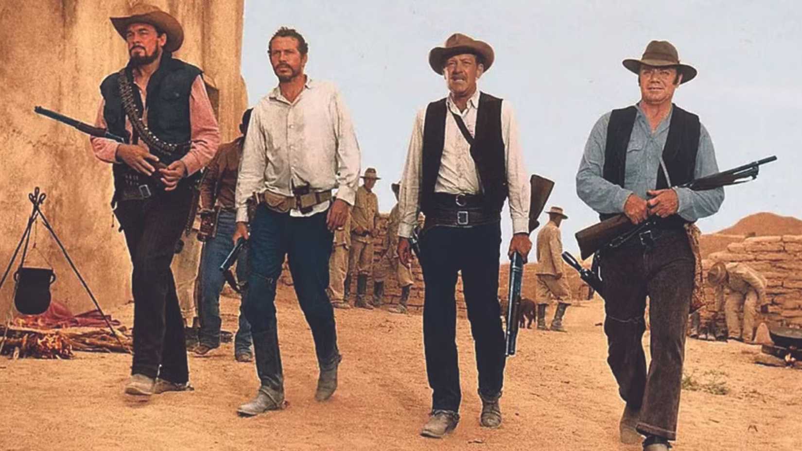 A turma andando pela rua com armas em The Wild Bunch