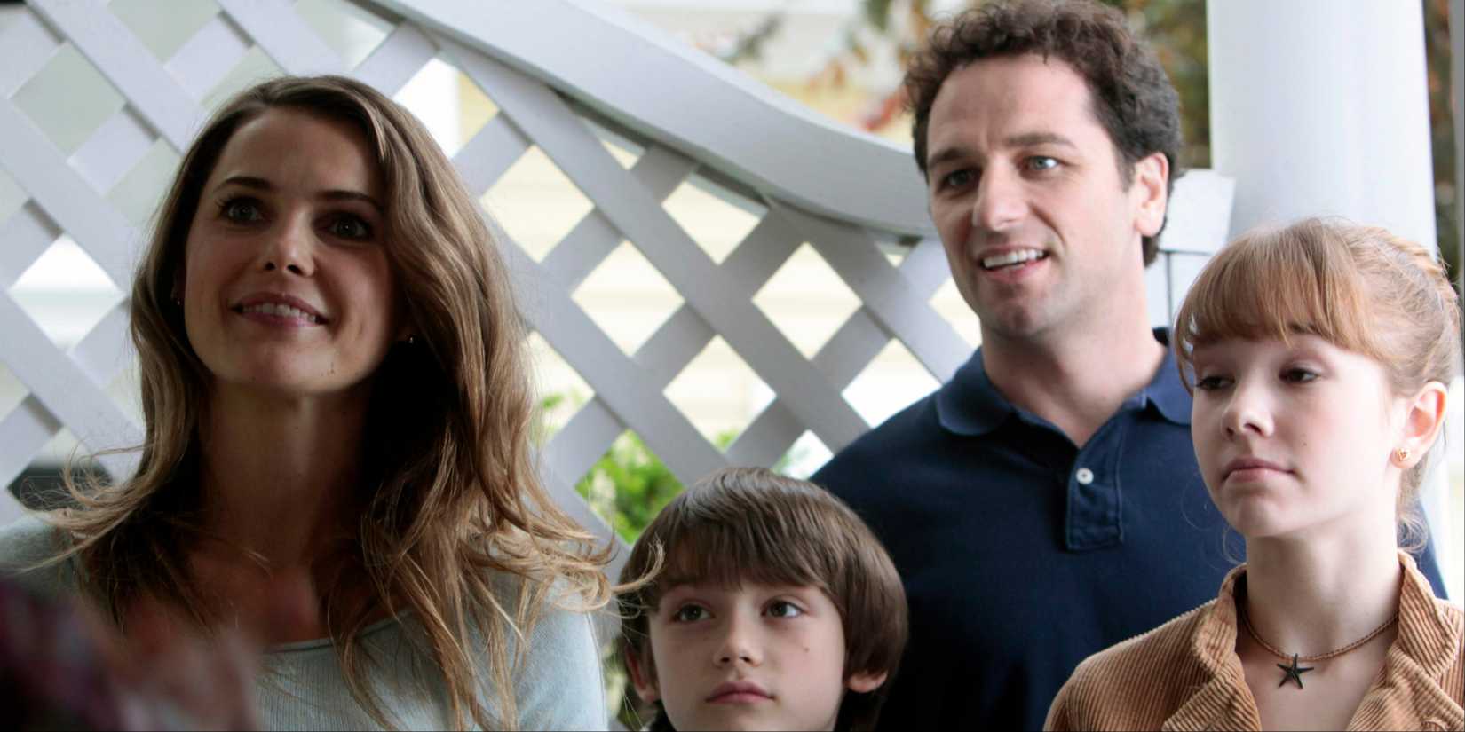 A família Jennings em frente a uma cerca, Elizabeth (Keri Russell) segurando um prato de comida em The Americans
