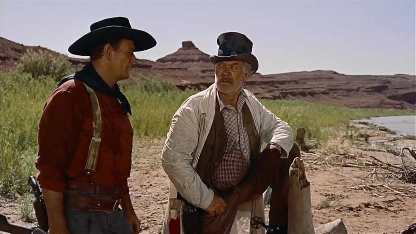 Ward Bond hitches his leg up on a post to talk to John Wayne in The Searchers