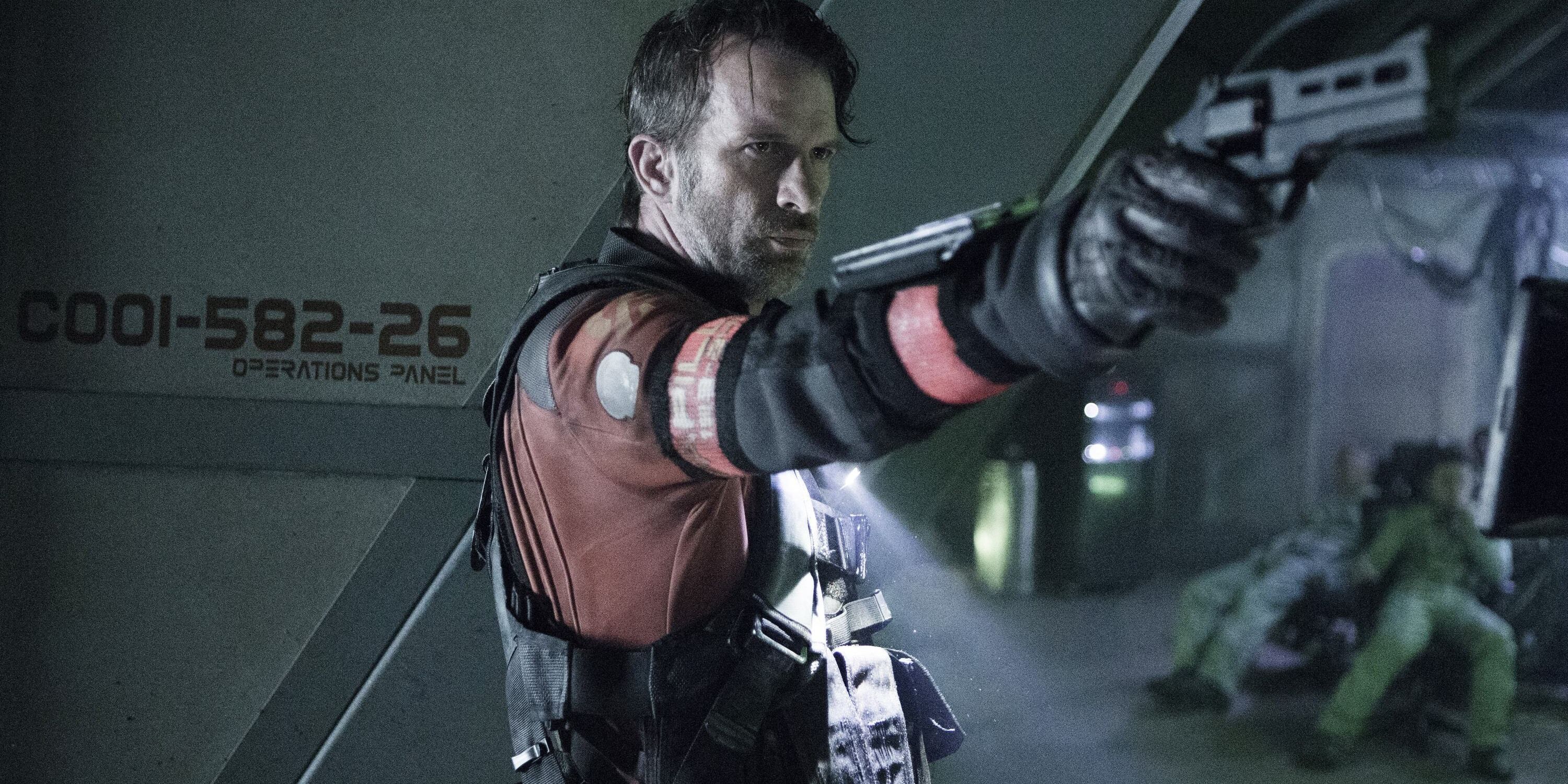 Thomas Jane como Joe Miller em The Expanse, apontando uma arma.