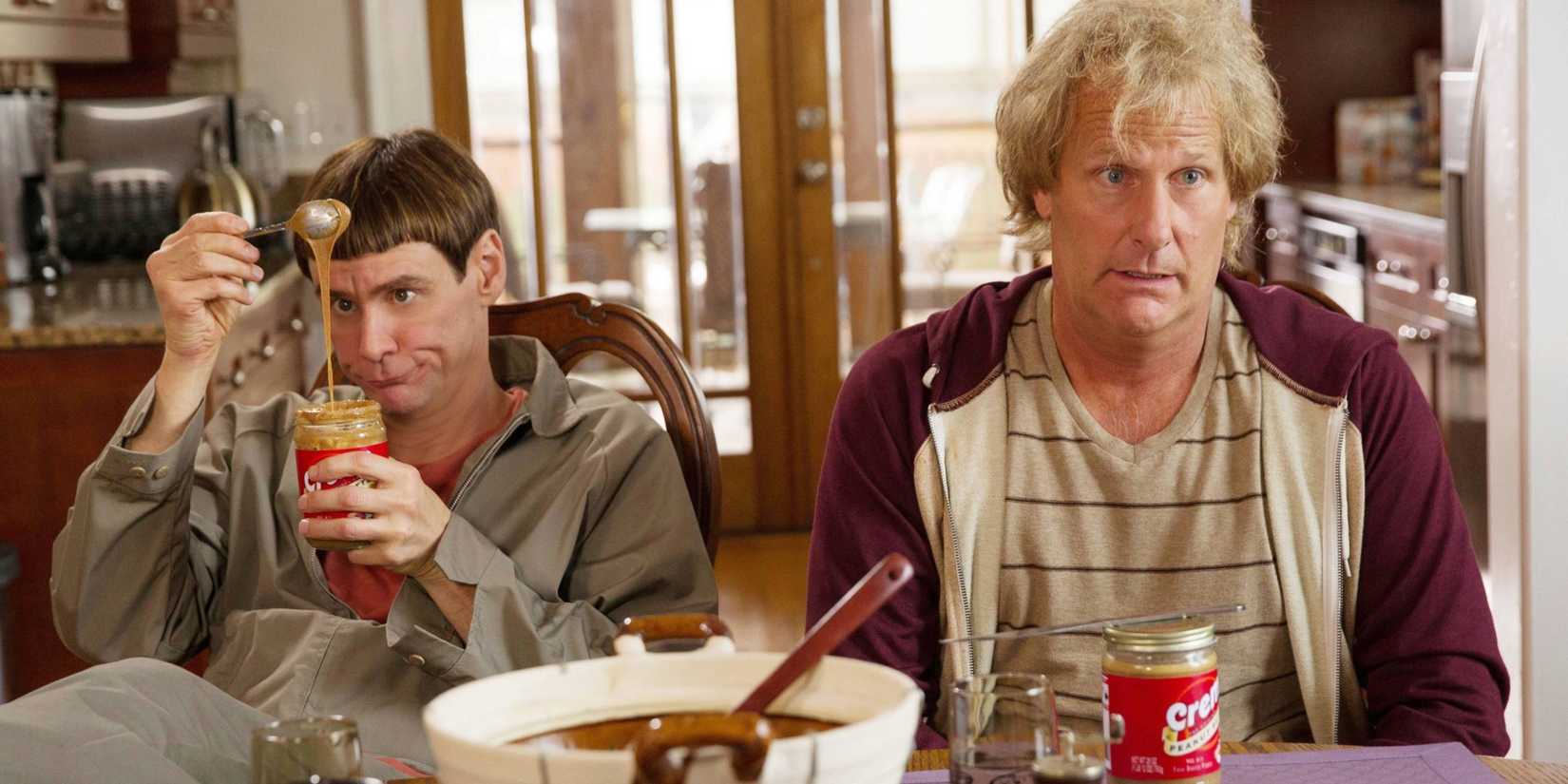 Harry looking at a spoonful of peanut ʙuттer with Lloyd next to him, the pair sitting in front of baking supplies at a table, in Dumb And Dumber To.