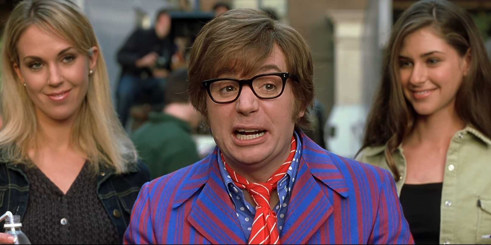 Austin sat on the set of his film, talking to Steven Spielberg off-screen, with two women behind him in Austin Powers in Goldmember.