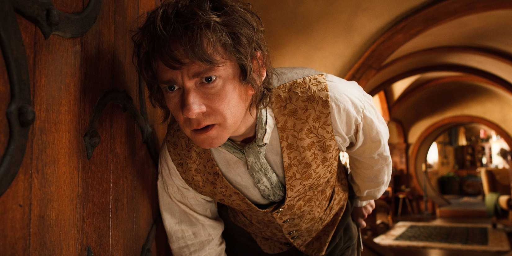 Bilbo Baggins crouching down and leaning against the wall in his house, looking perplexed, in The Hobbit: An Unexpected Journey.