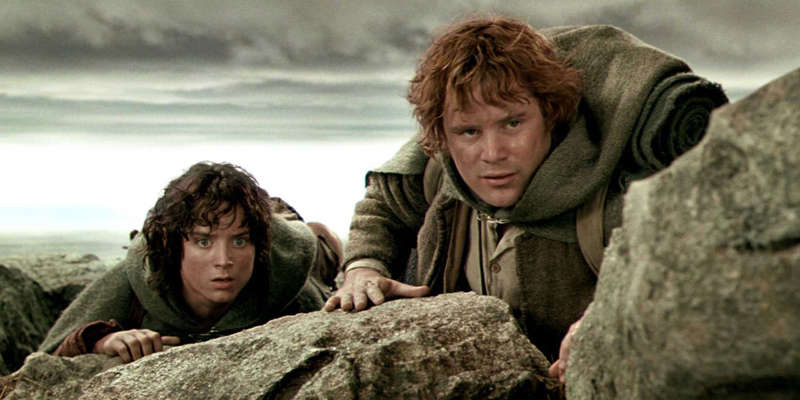 Sam and Frodo peering over a rock, staring intently at something in the distance, in The Lord of the Rings: The Two Towers.