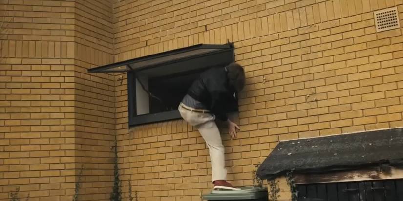 Alan Partridge climbing into a window, his trousers falling down, after getting locked out in Alan Partridge: Alpha Papa.