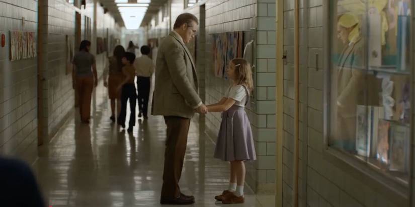 Principal Wade holding a little girl's hands in the school corridor