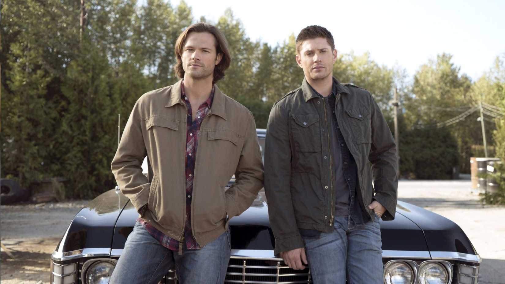 Dean and Sam Winchester leaning against a car