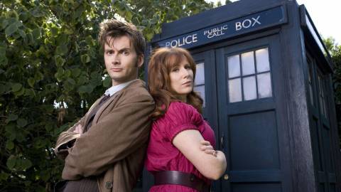 Donna and The Doctor standing back to back in front of the TARDIS