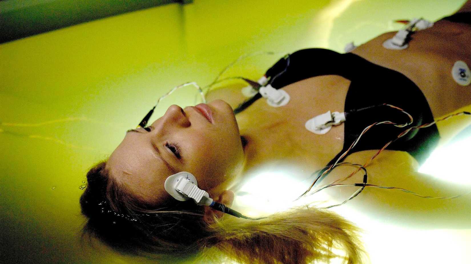 Anna Torv flutuando em uma piscina com monitores em Fringe