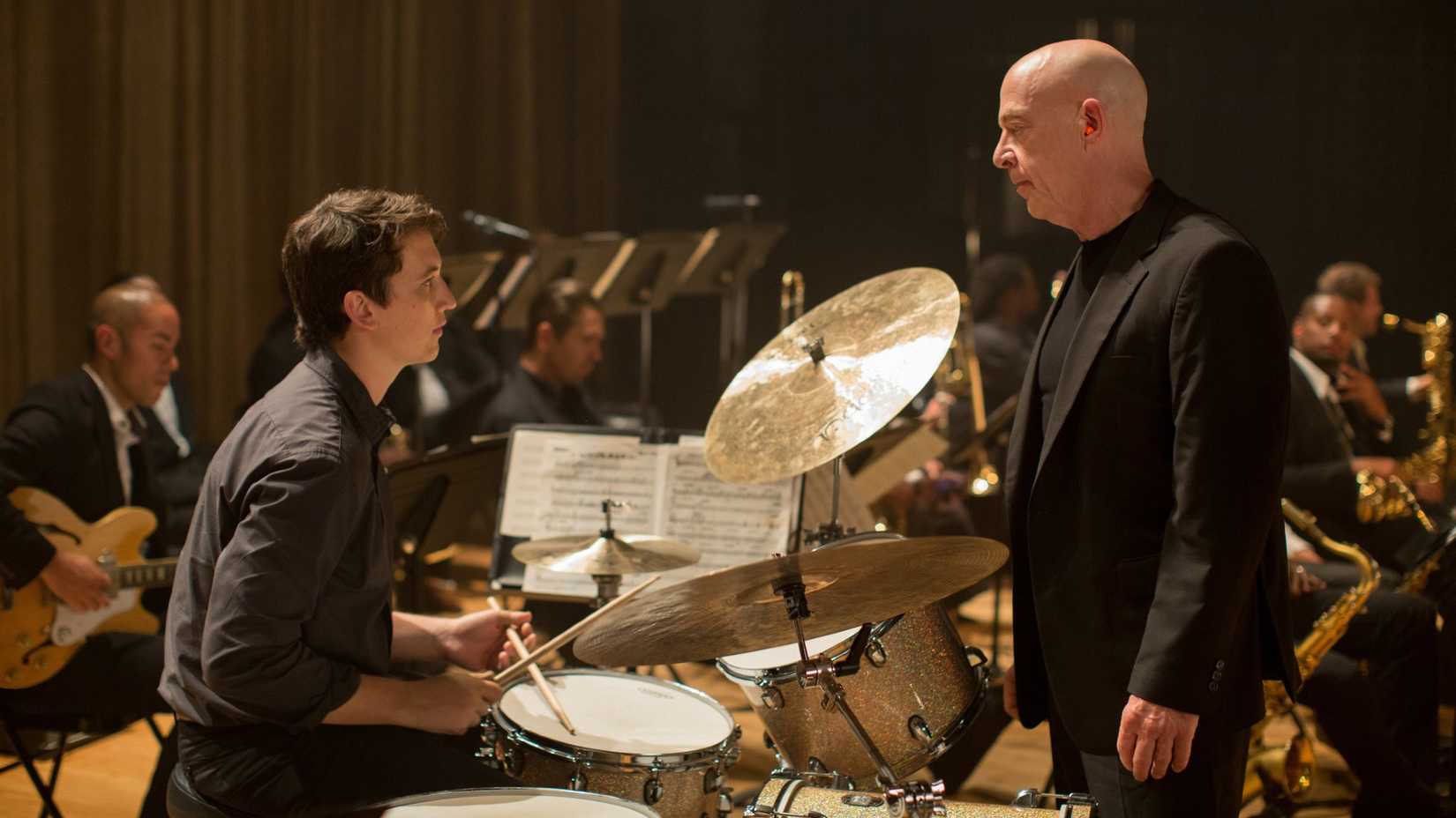 Miles Teller sits behind a drumset as he talks to J.K. Simmons in Whiplash