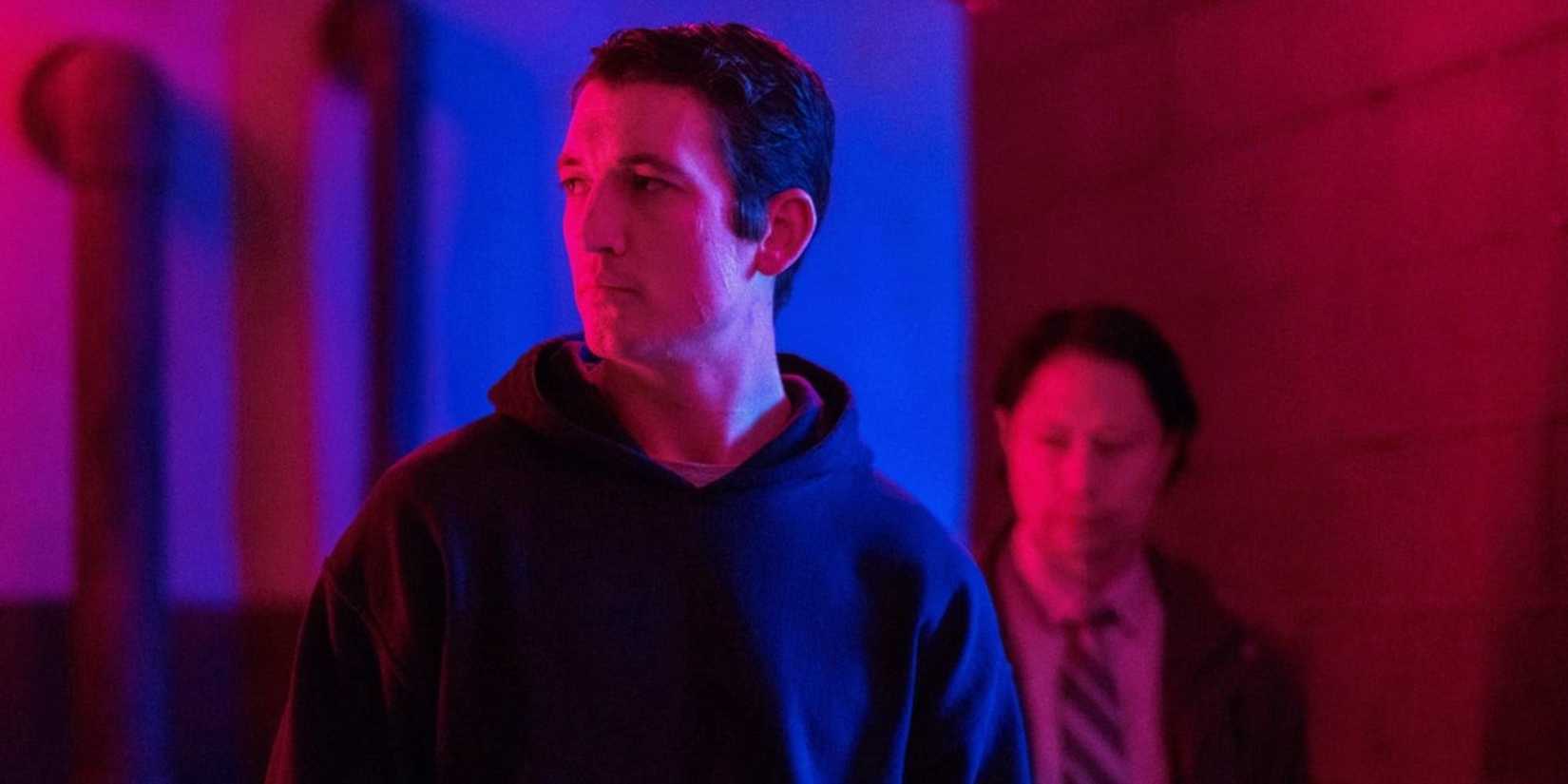 Martin Jones (Miles Teller) walking in a blue and red hallway in Too Old to Die Young.