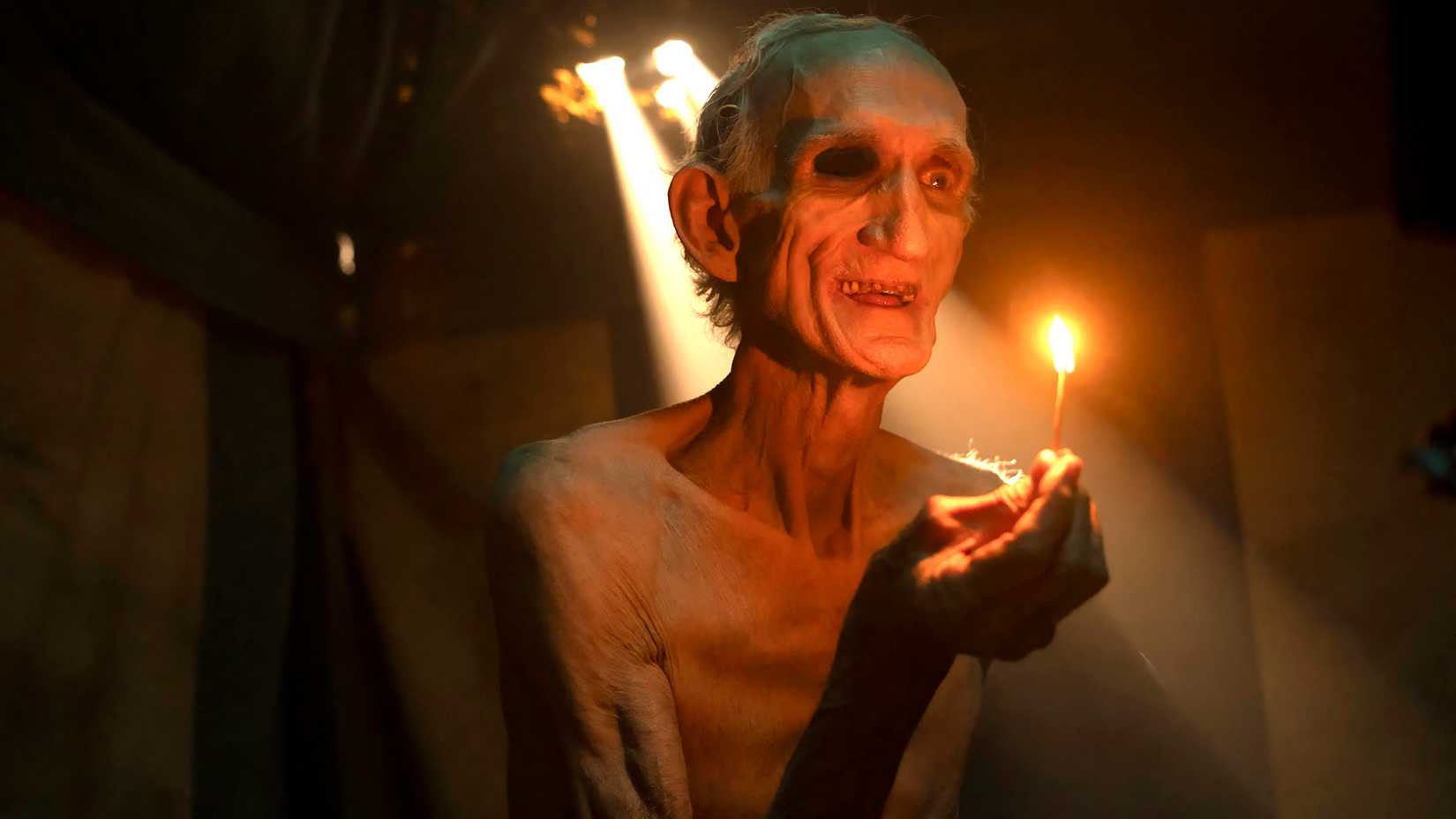 A creepy form of Pennywise holding a lit match in IT: Welcome to Derry Episode 3