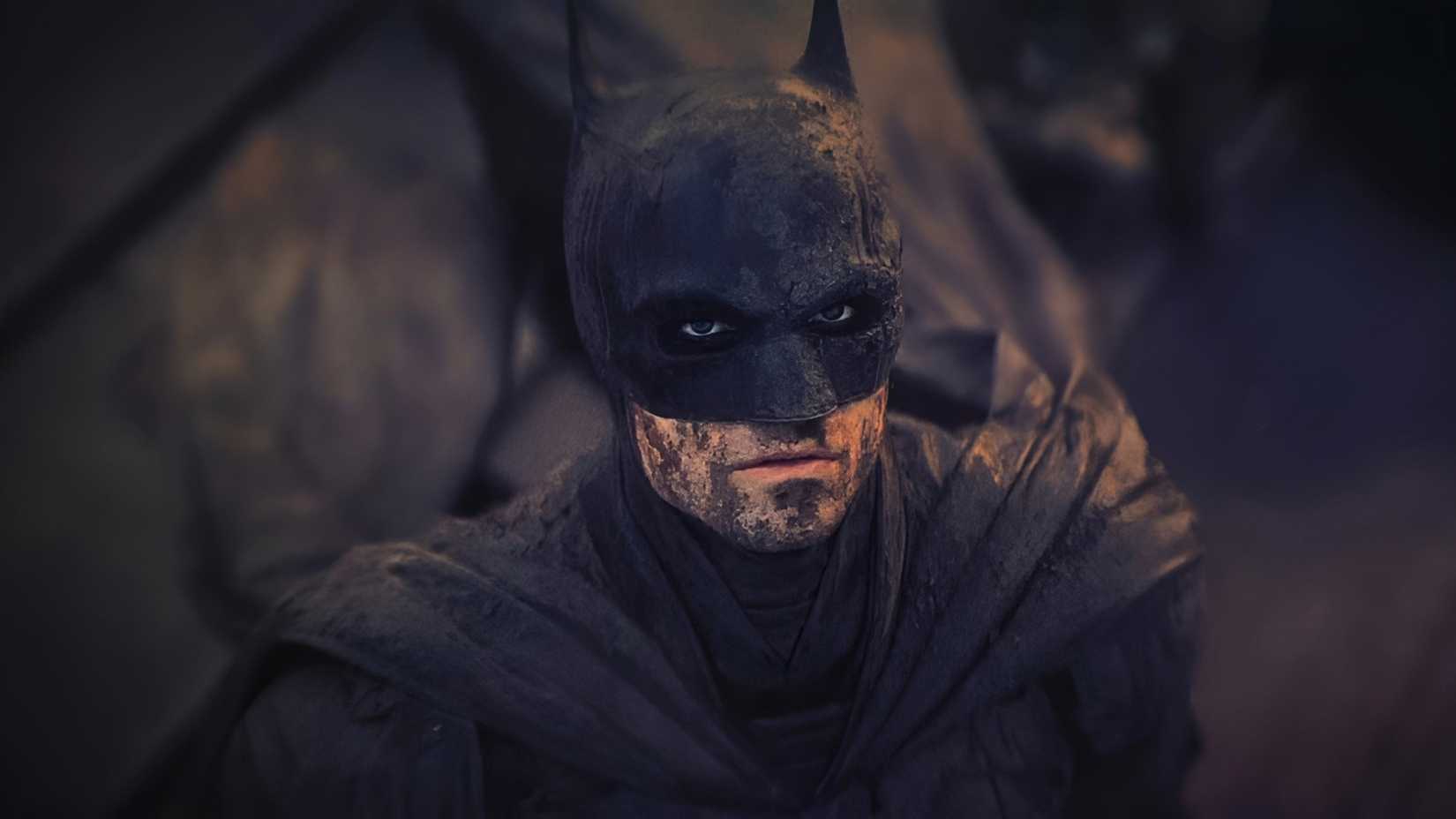 Batman de Robert Pattinson com sujeira no rosto e traje, olhando para cima em The Batman