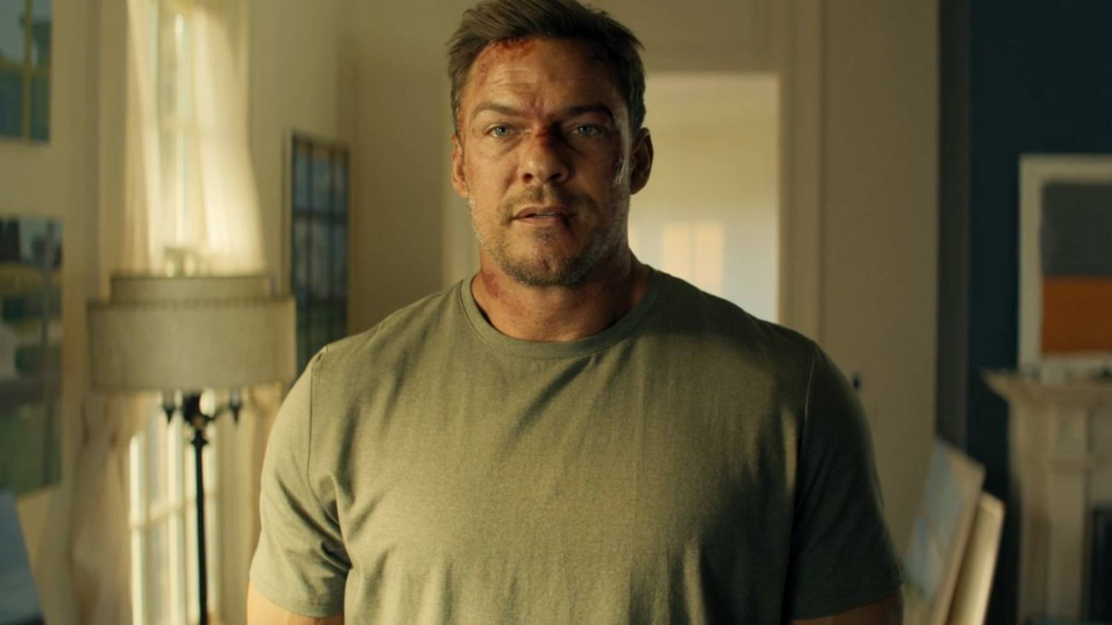 Alan Ritchson looks forward with a serious expression in a scene from Reacher season 3