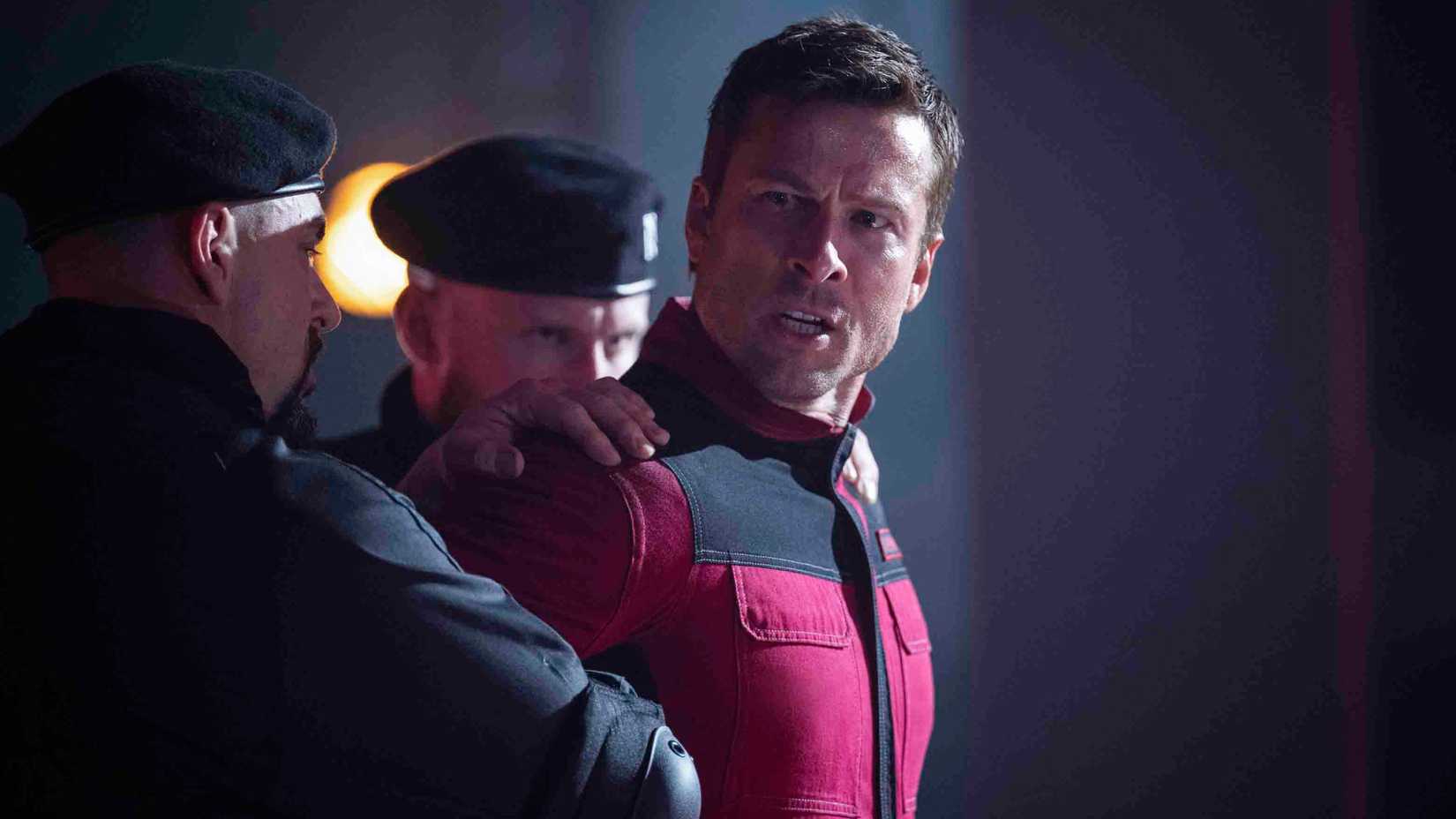 Ben Richards sendo contido por guardas em 'The Running Man'