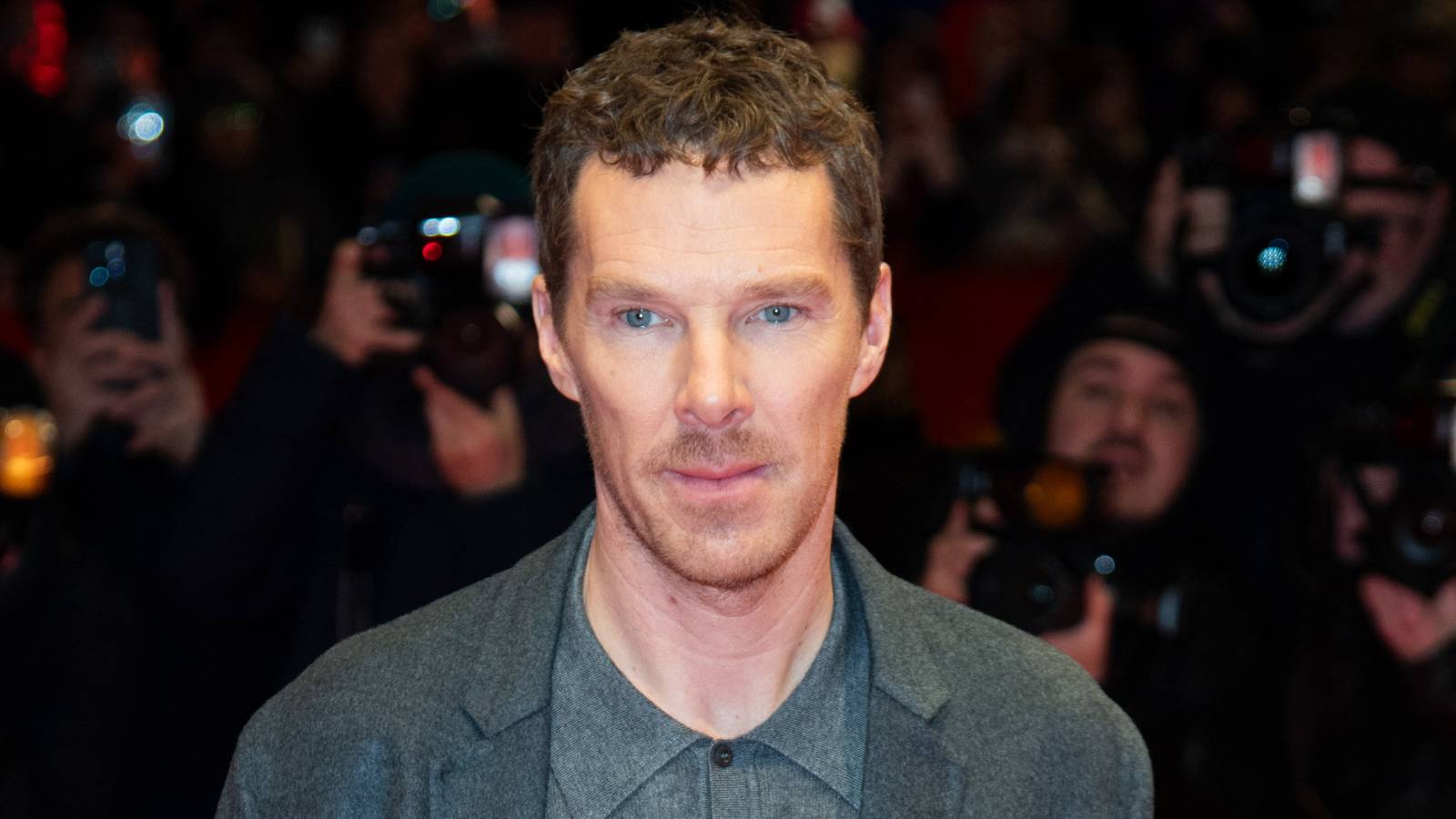 Benedict Cumberbatch looks forward with a neutral expression while attending a red carpet event.