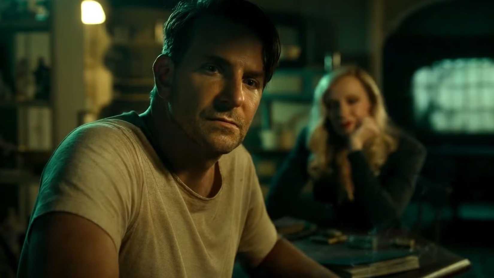 Bradley Cooper sentado no escuro em O Beco do Pesadelo