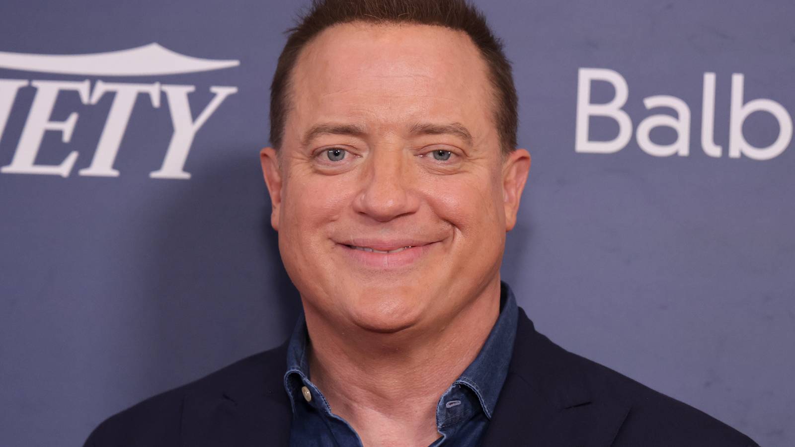 Brendan Fraser smiling in front of a step-and-repeat