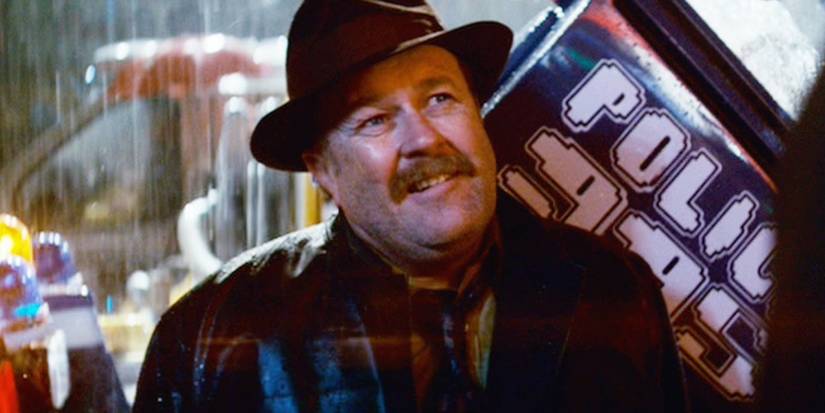 Bryant sorrindo em frente a um carro de polícia em Blade Runner
