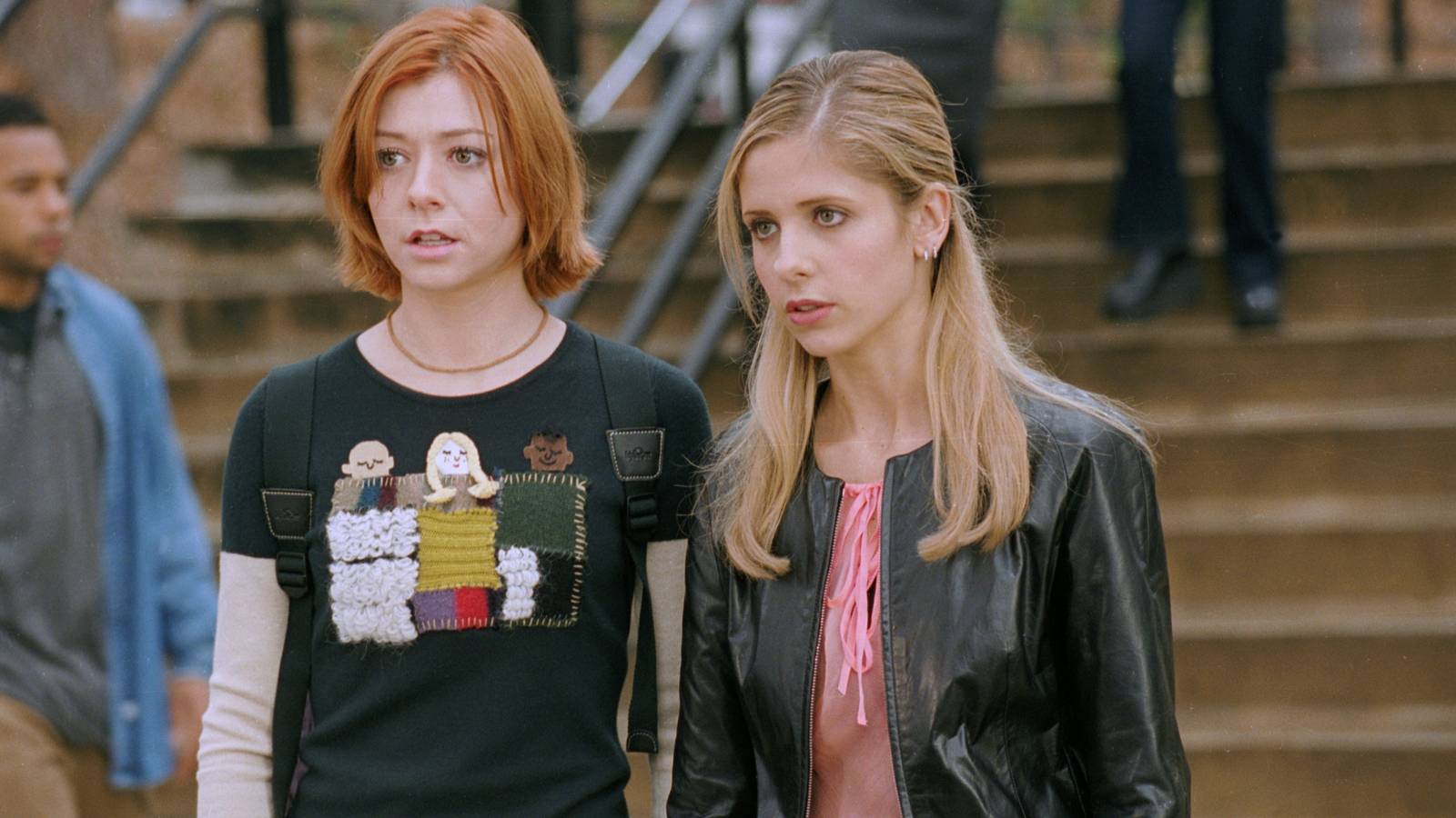 Buffy (Sarah Michelle Gellar) and Willow (Alyson Hannigan) looking intently at Faith (Eliza Dushku) on Sunnydale campus in Buffy the Vampire Slayer season 4, episode 15